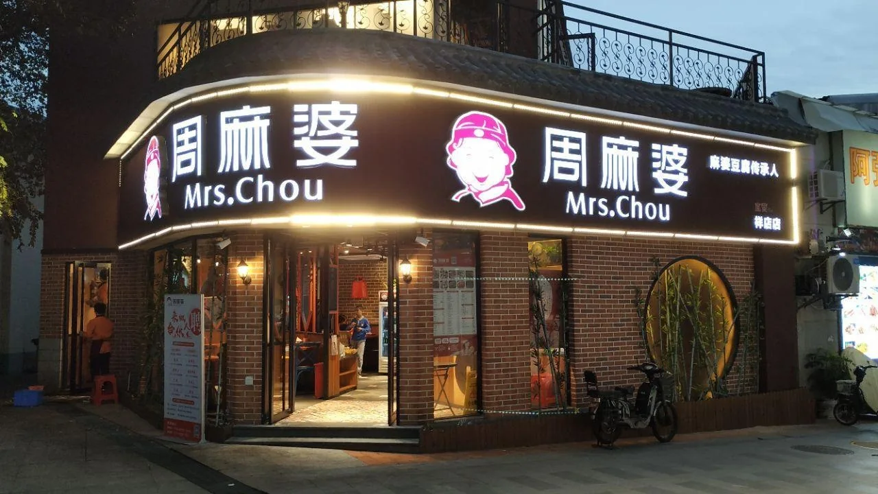 Illuminated restaurant signage on a commercial storefront at dusk